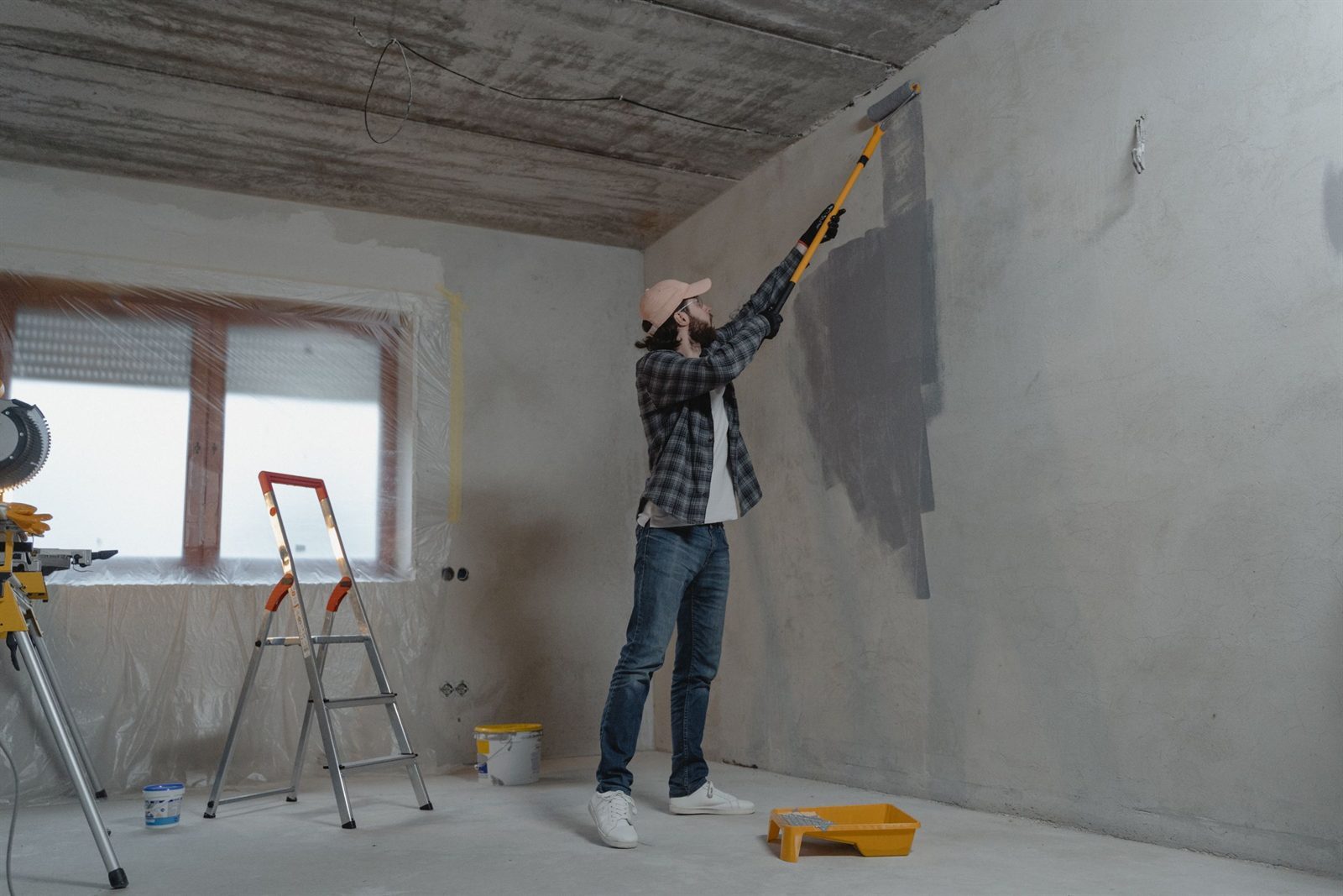 Decorator painting an interior wall with a roller