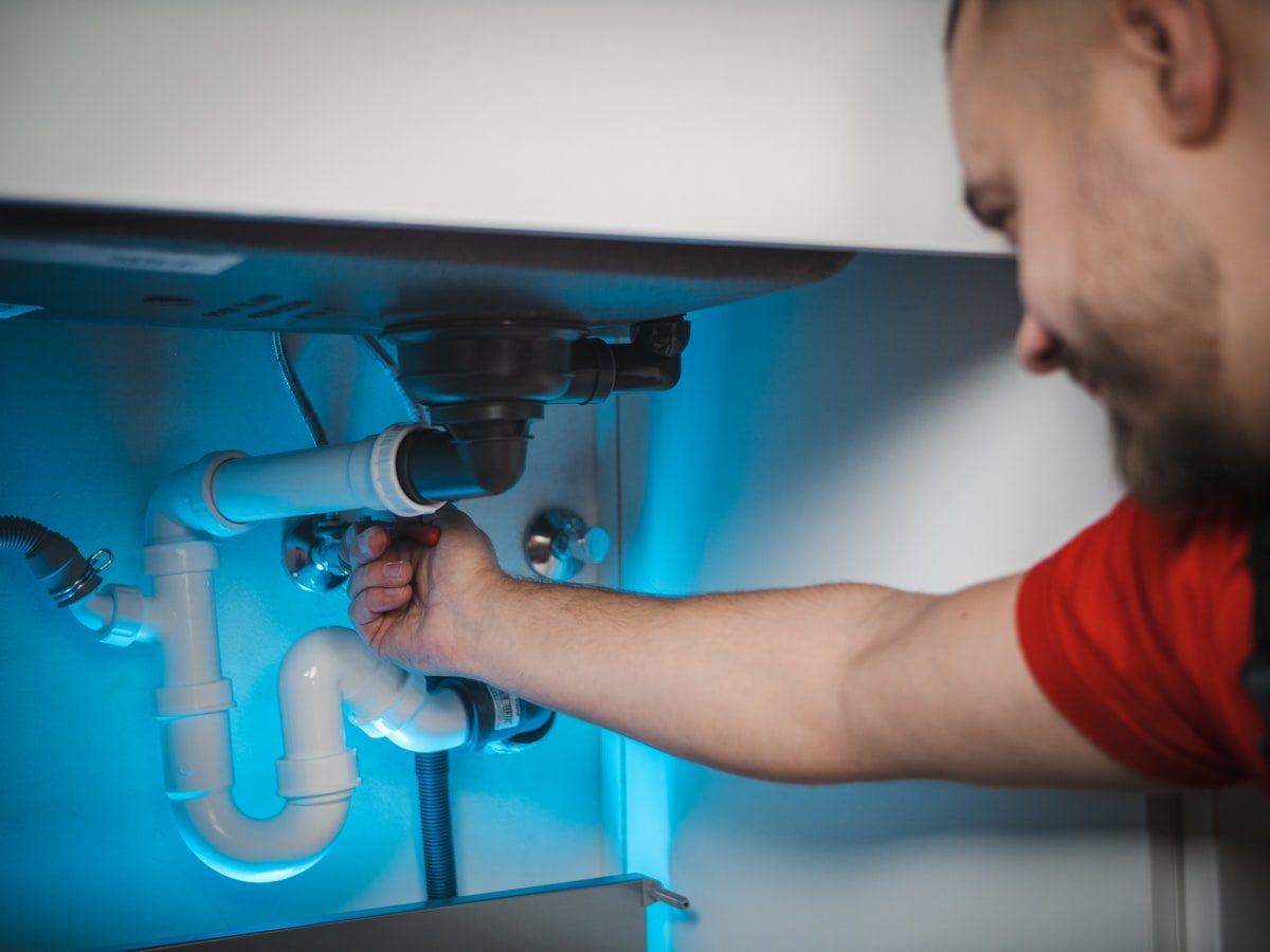 Plumber working on pipework beneath a basin